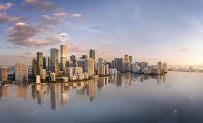 City skyline reflected in water at sunset with a building marked by the text 