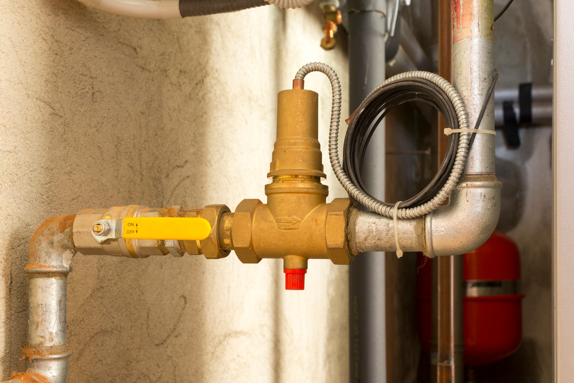 A close up of a valve on a pipe in a room.