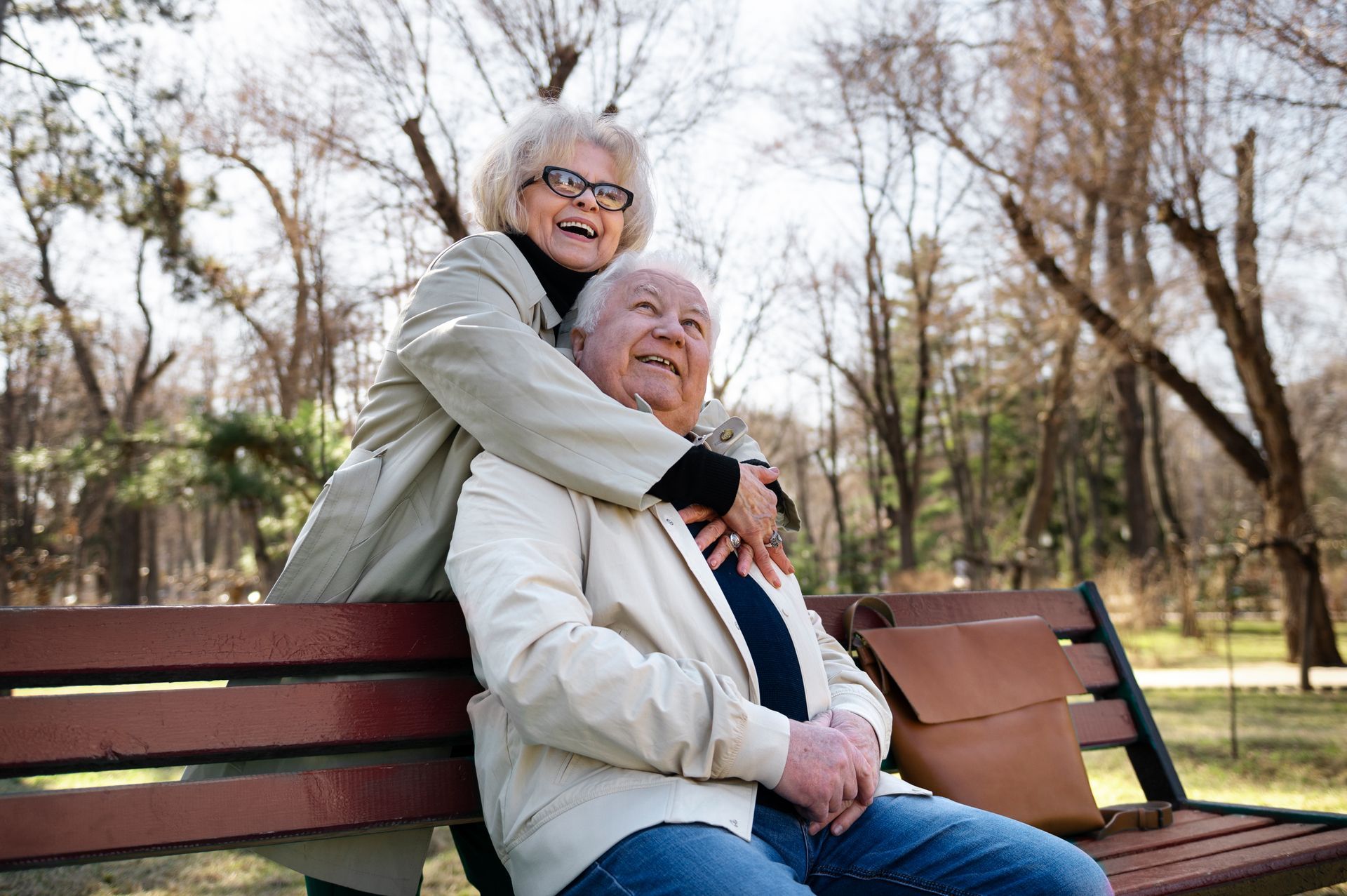An elderly couple is sitting on a park bench.