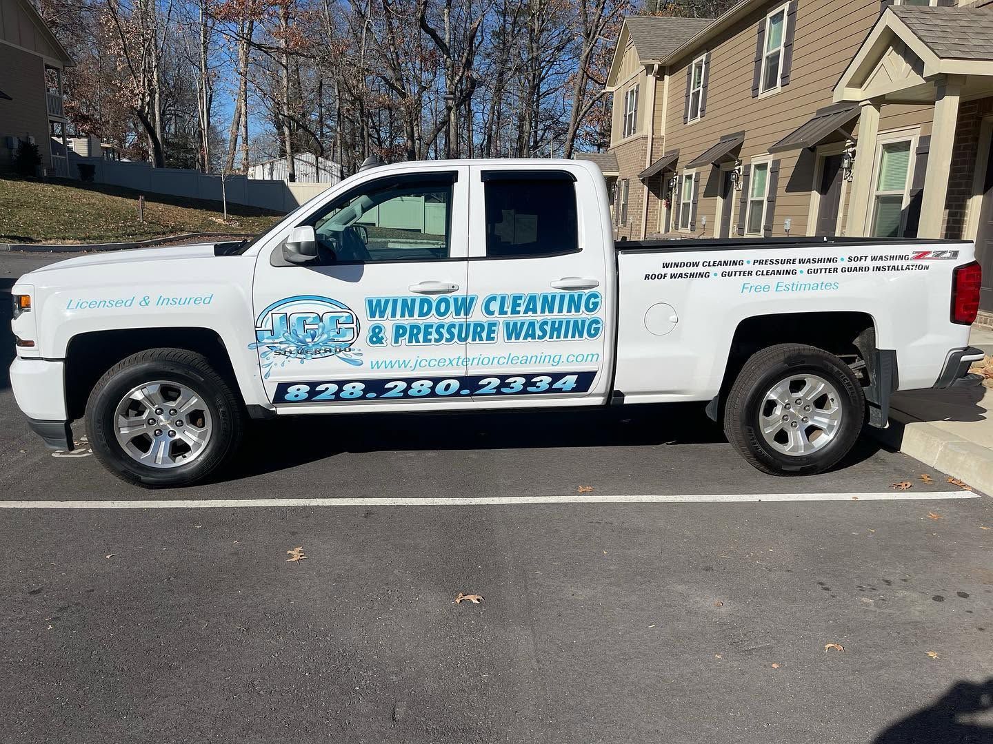 White pickup truck with “Window Cleaning & Pressure Washing” signage parked on a street