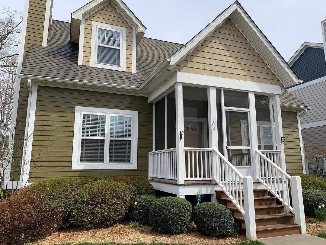 Two-story beige house with white trim, dormer windows, and a small front porch with steps