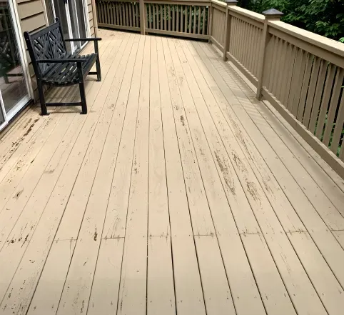 Empty wooden deck with a black bench and railing along the side