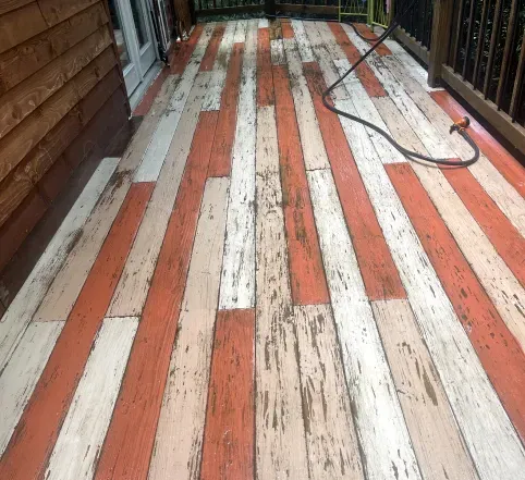 Weathered striped wooden porch deck with a black hose along the right side