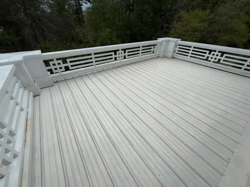 White wooden deck with railing overlooking trees and greenery