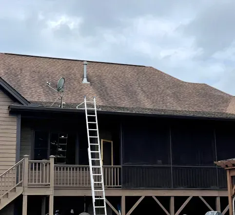 House with a long ladder leaning against the roof near a covered porch