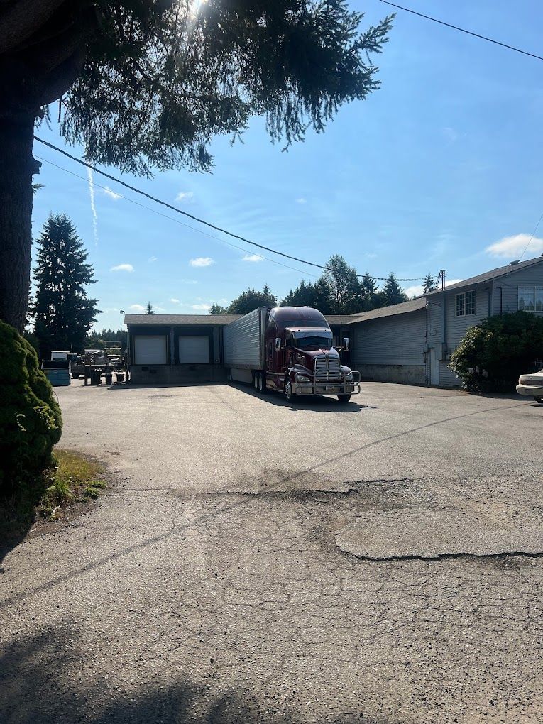A semi truck is parked in a parking lot in front of a building.