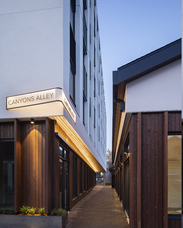 Exterior view of Canyons Alley, a narrow walkway between modern buildings, with a street sign.