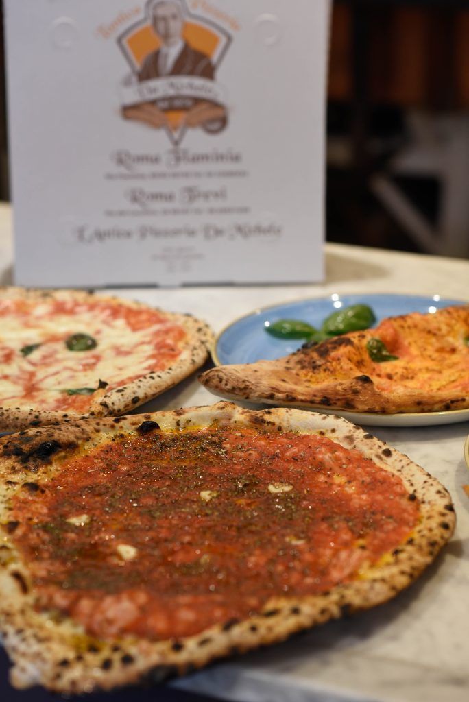 Pizze con vari condimenti, primo piano, scatola con logo sullo sfondo su una superficie di marmo.