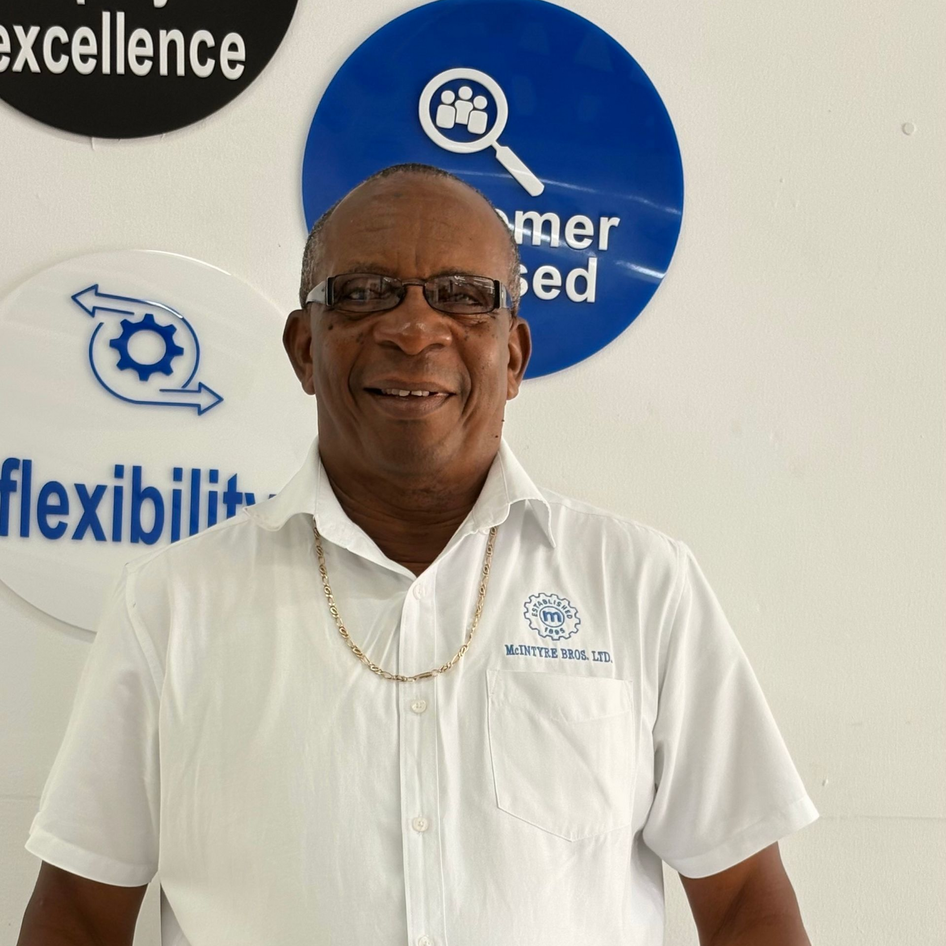A man in a blue shirt is standing in front of a wall with circles that say honesty and integrity