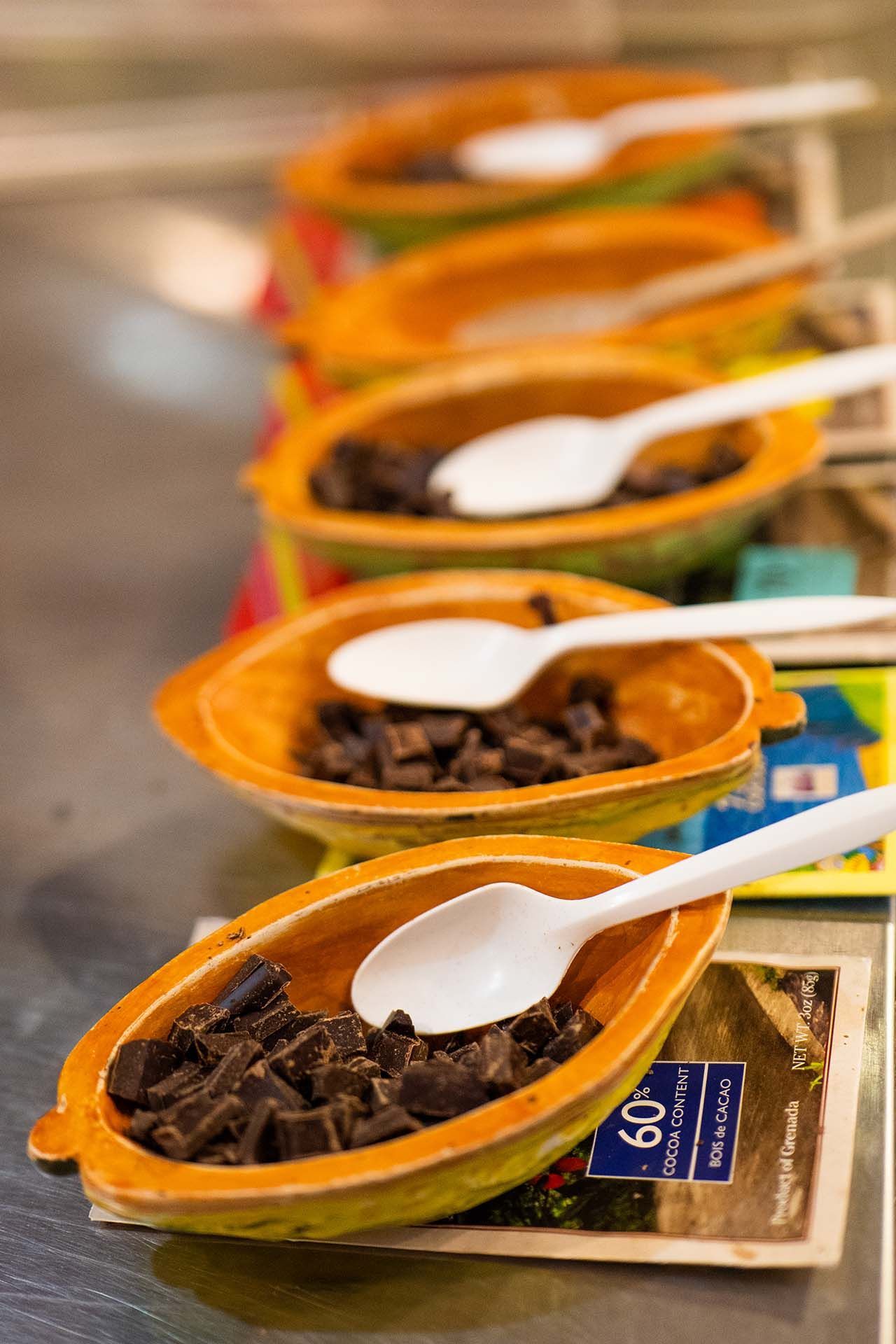 A row of bowls filled with chocolate chips and spoons.