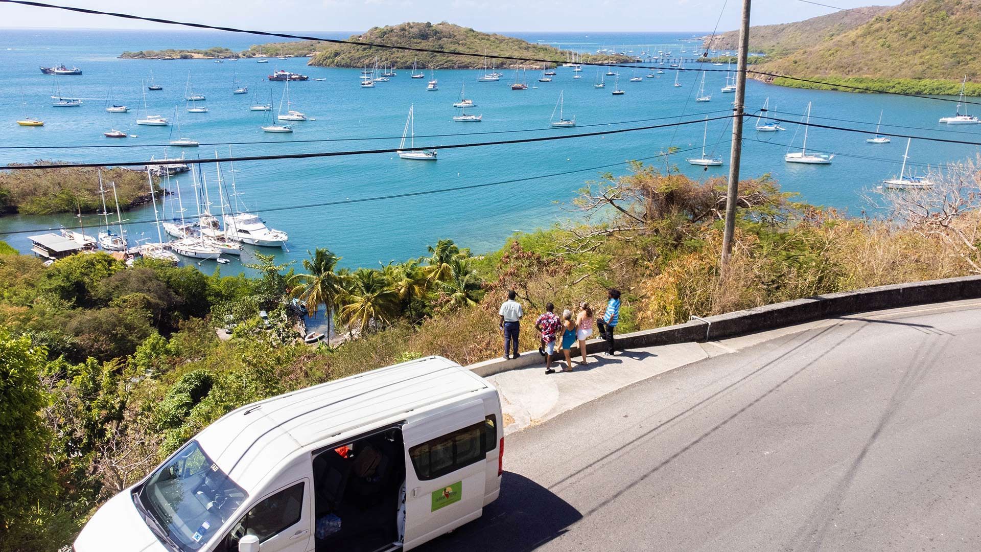 A white van is parked on the side of a road next to a body of water.