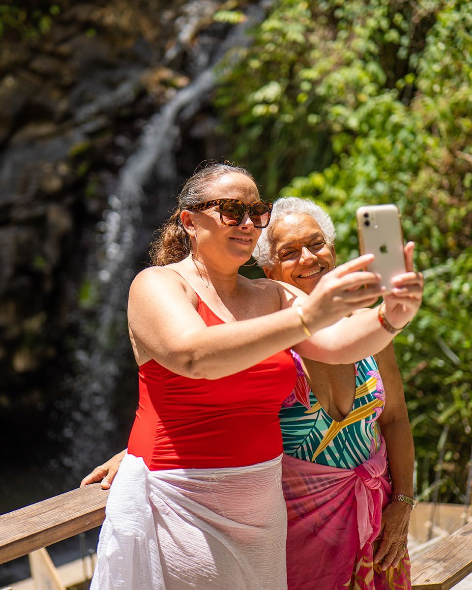 Two women are taking a selfie in front of a waterfall.