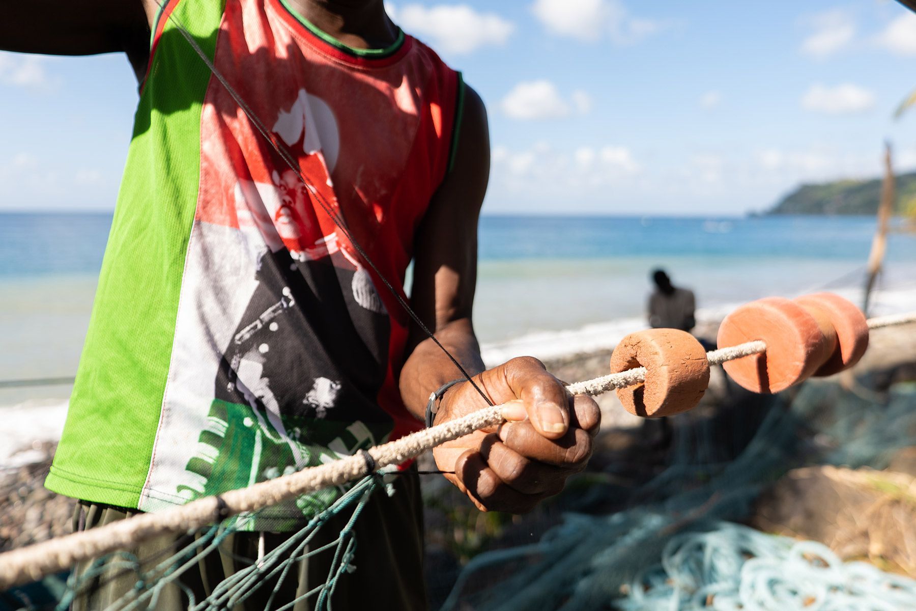 A man in a green and red tank top is holding a fishing net.