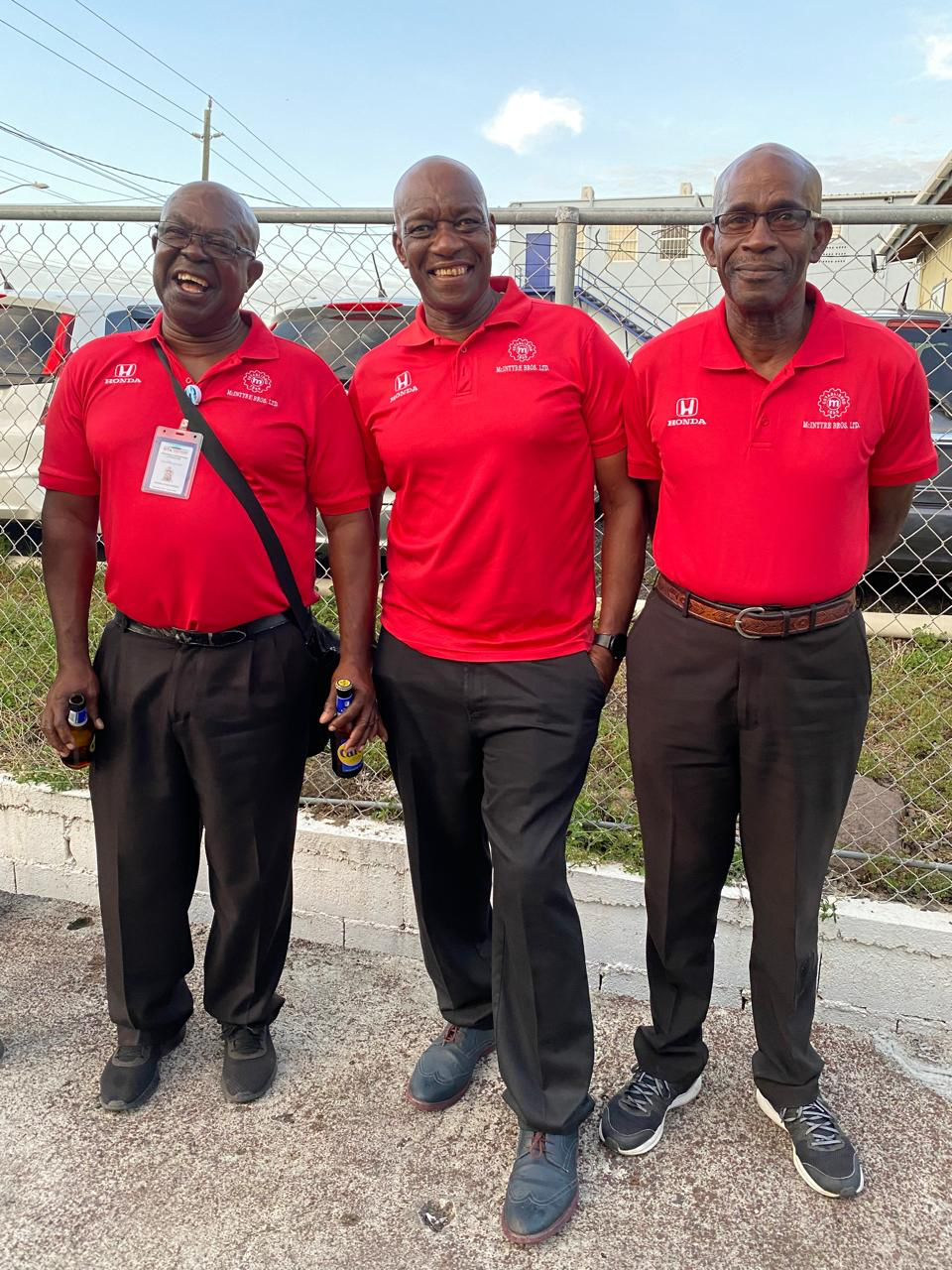 Three men in red shirts are standing next to each other