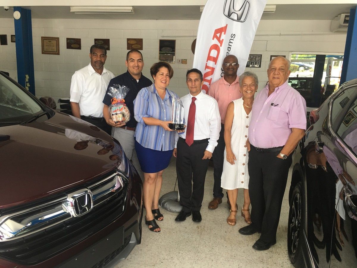 A group of people standing in front of a honda car