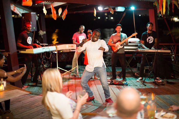 A man is dancing on a stage in front of a band.