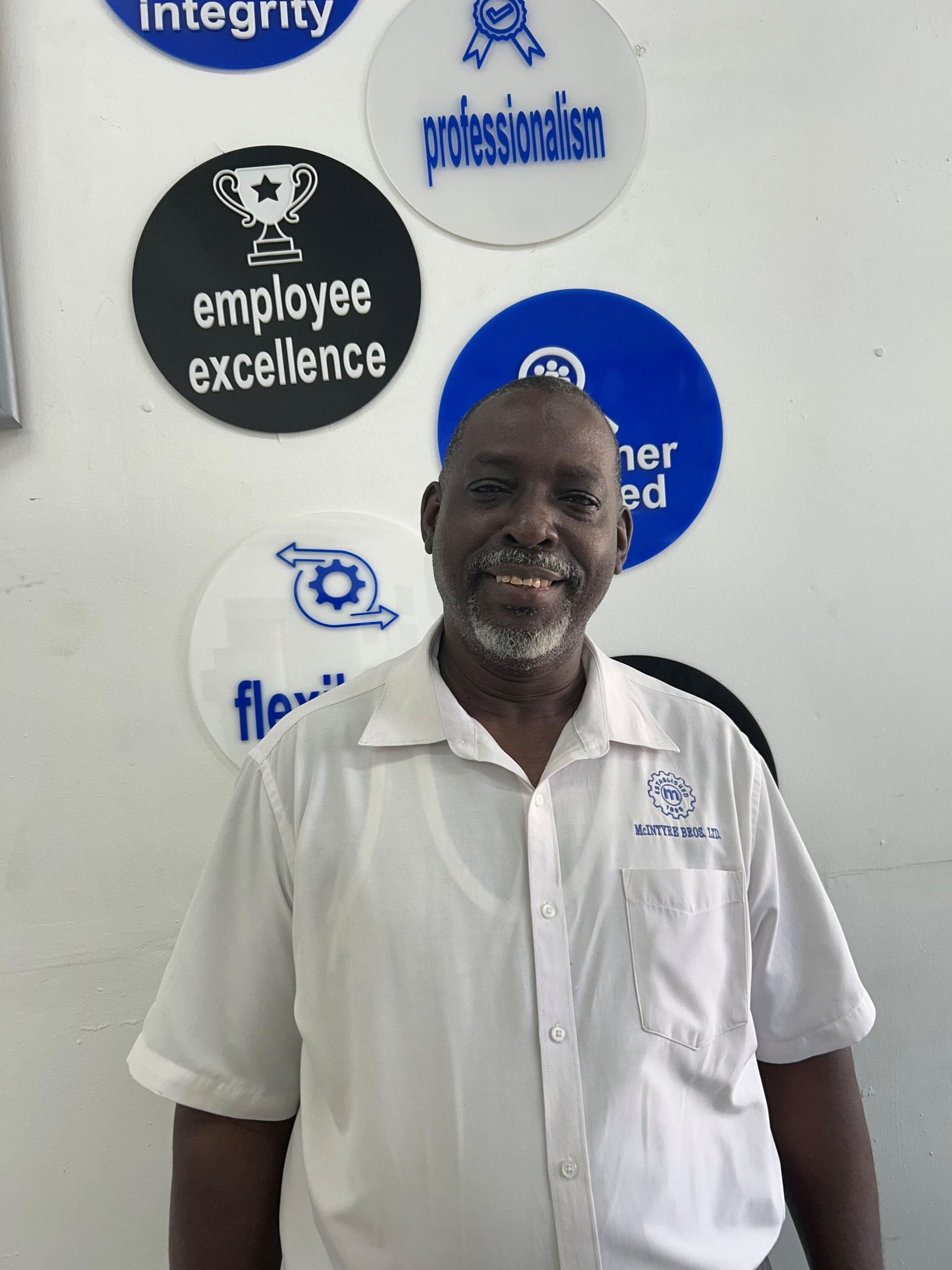 A man in a white shirt is standing in front of logos