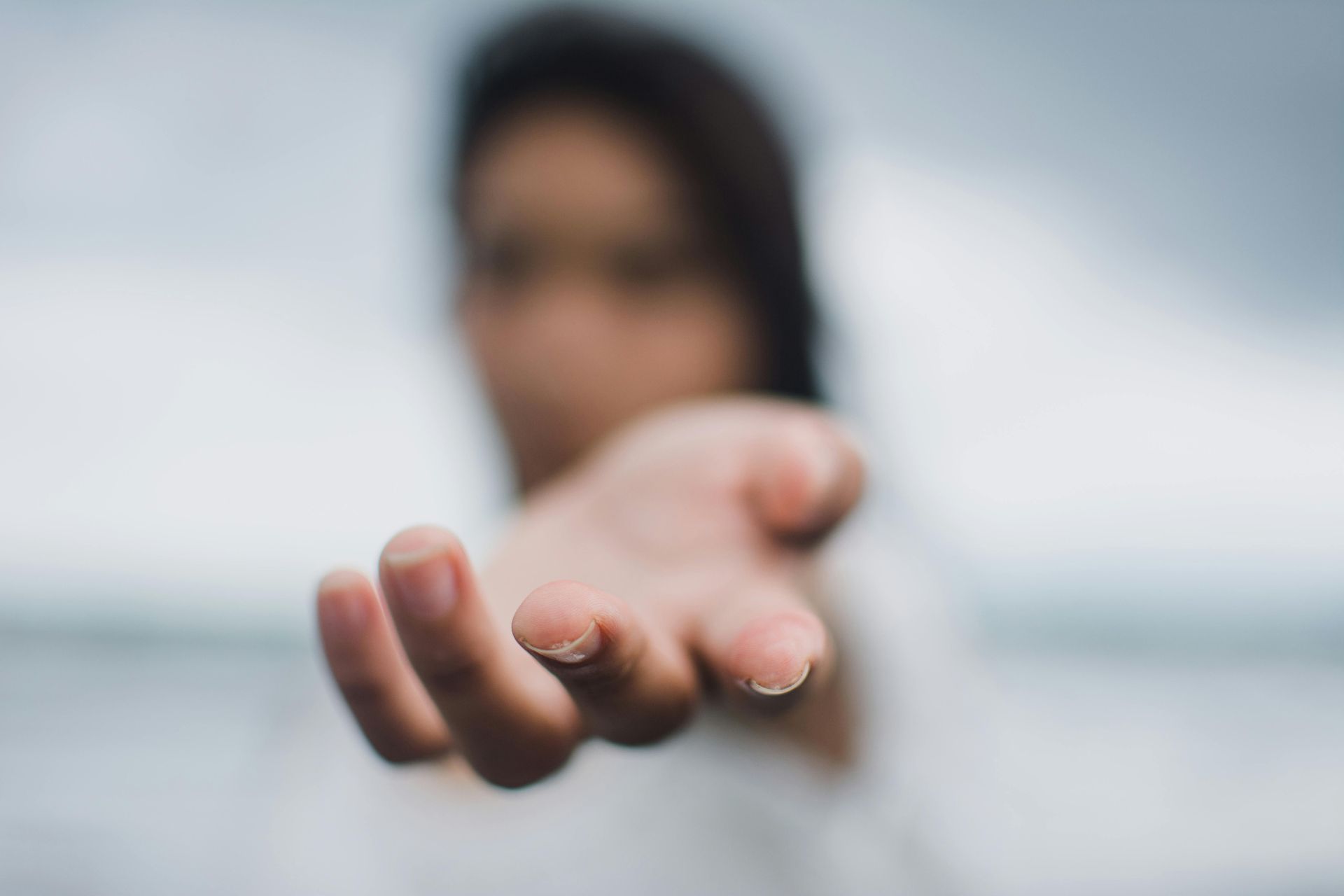 A woman is reaching out her hand towards the camera.
