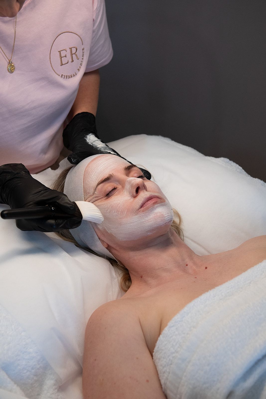 Person Receiving Facial Treatment; Esthetician Applying Mask With Brush — Eternal Radiance in Strathmore, VIC