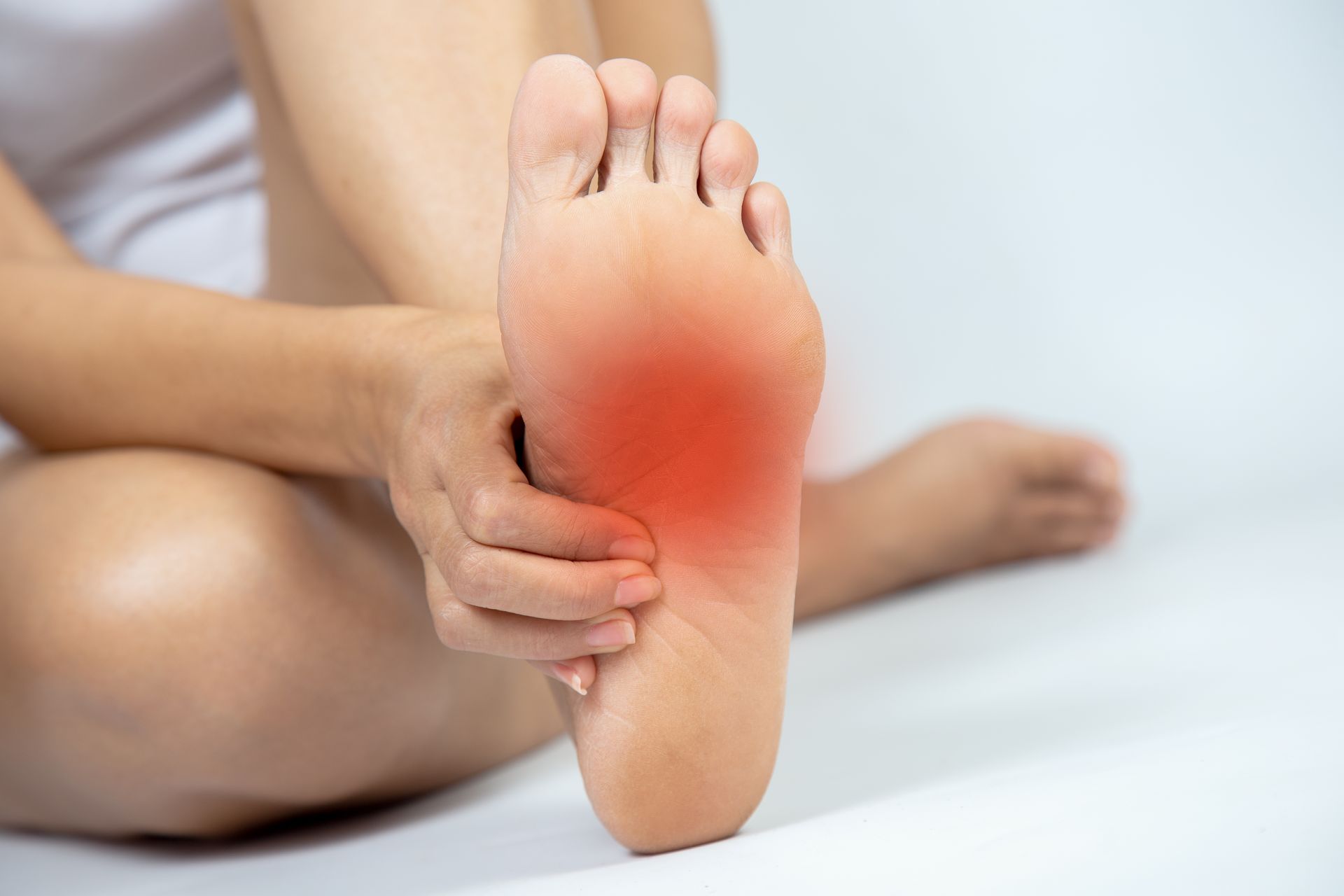 Person holding foot with a red highlighted area indicating pain.