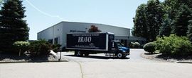 A blue and white truck is parked in front of a building.