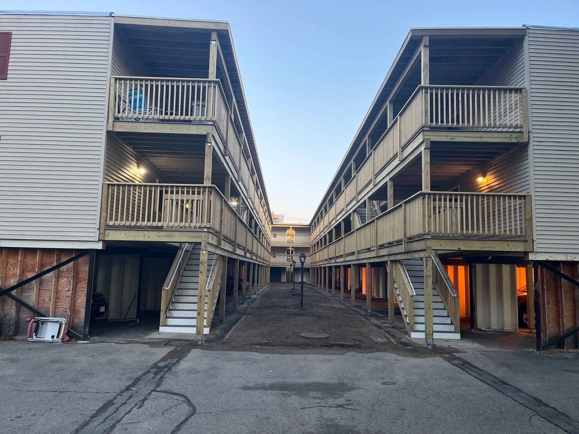 The Milestone Condominium decks. Two connected multi-story buildings with wooden balconies, stairways, and a center pathway.