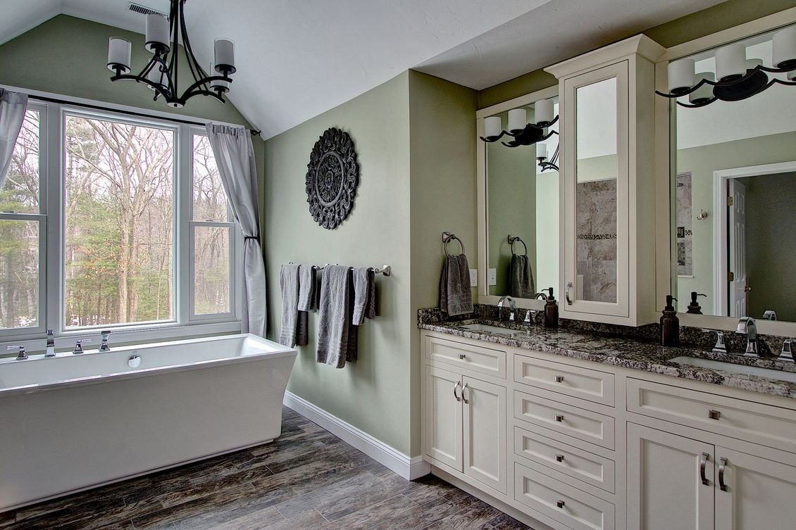 Modern bathroom with white tub, double vanity, and green walls.