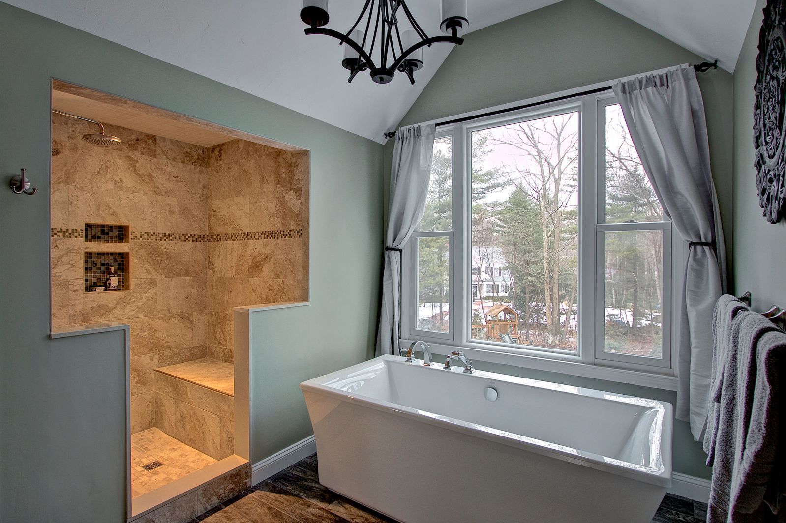 Modern bathroom with a walk-in shower, freestanding tub, large window, and light green walls.