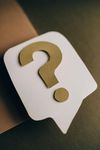 White speech bubble with a gold question mark against a brown and dark green background.