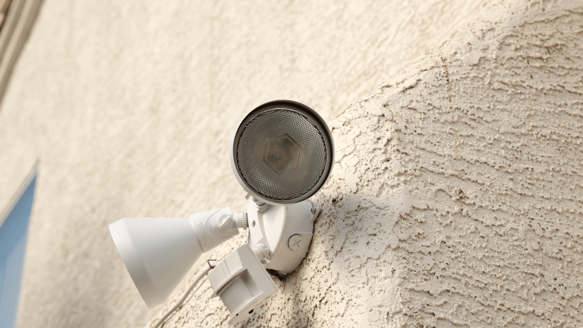 A white light is mounted on the side of a building.