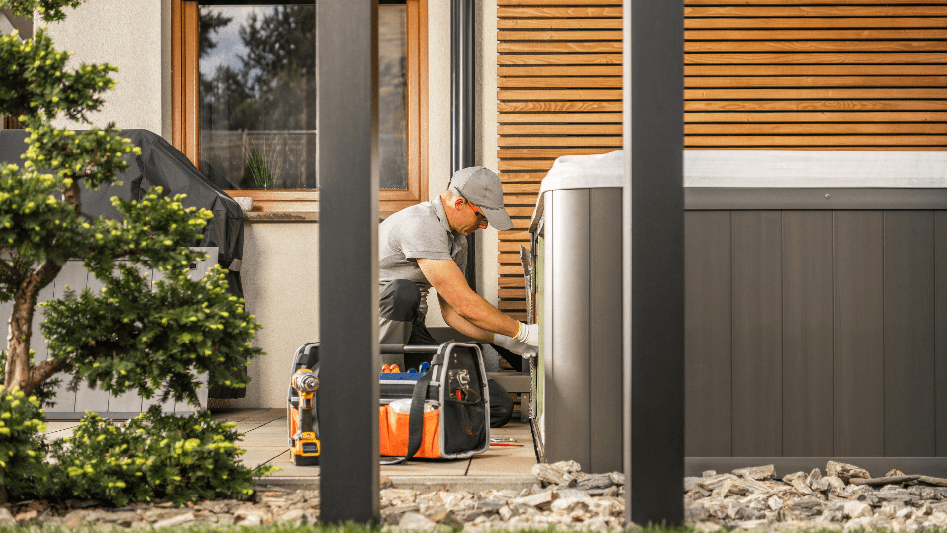 A man is working on a hot tub outside of a house.
