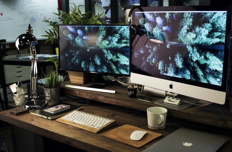 A desk with two computer monitors a keyboard and a mouse