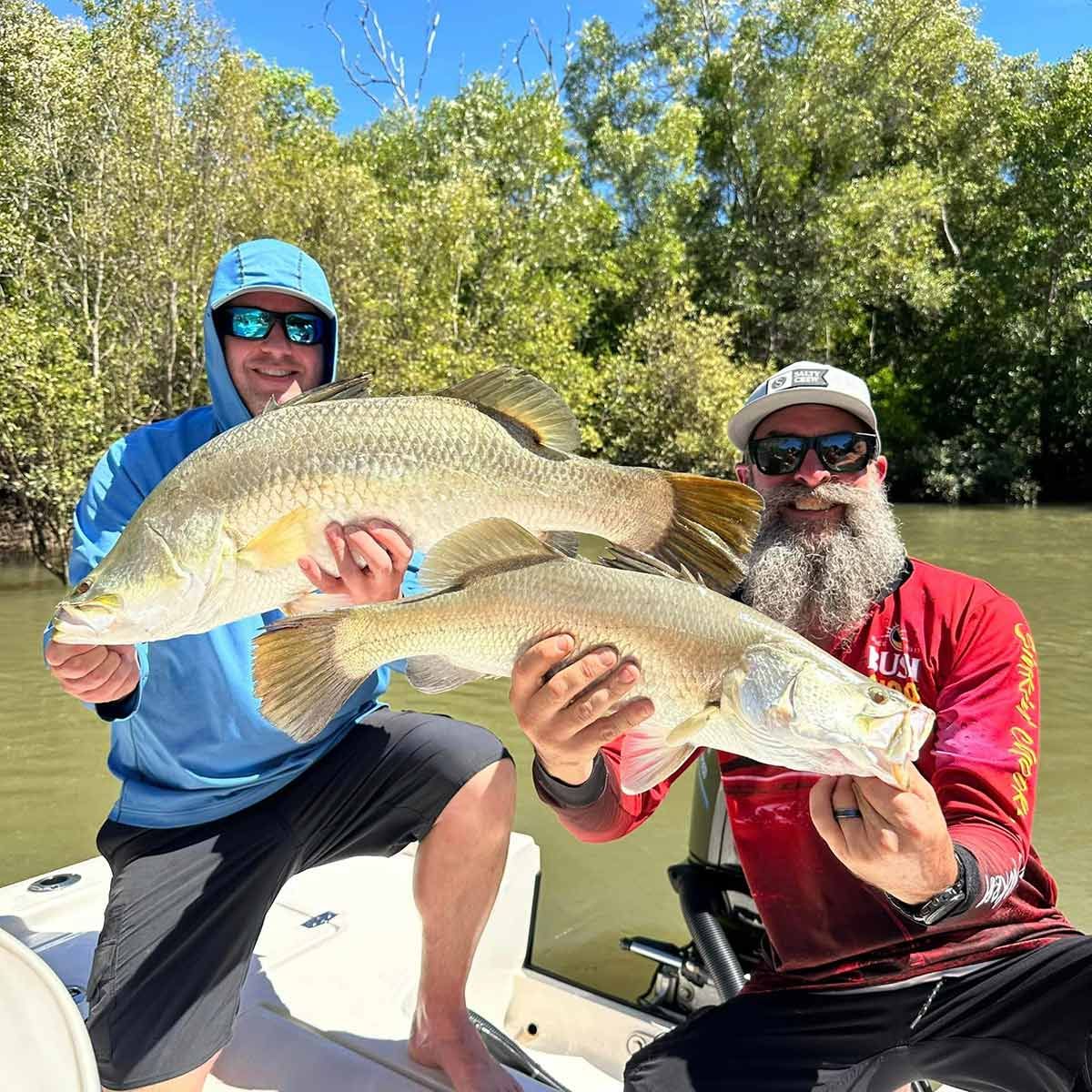 Two Men Are Sitting On A Boat Holding Large Fish — Territory Barra Sportfishing In Zuccoli, NT
