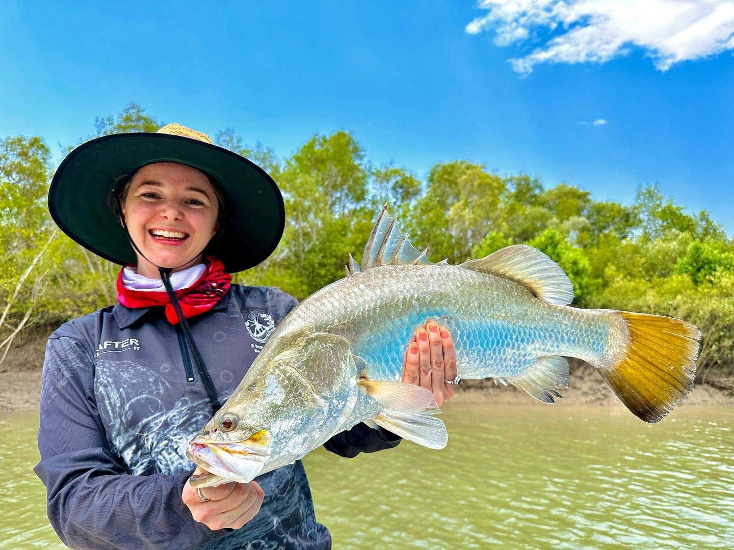 A Man Is Holding A Large Fish In His Hands While Sitting On A Boat — Territory Barra Sportfishing In Zuccoli, NT