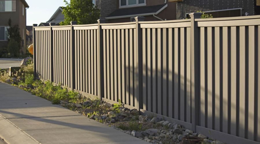 Modern grey composite privacy fence installed along a residential sidewalk in Florida.