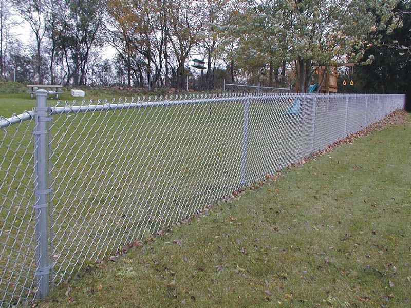 A chain link fence is surrounding a grassy field.