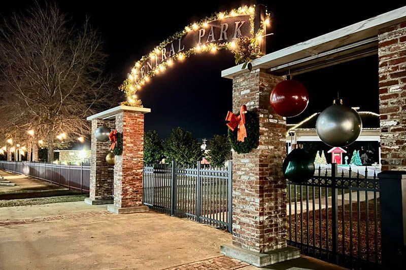 The entrance to a park is decorated with christmas decorations and lights.