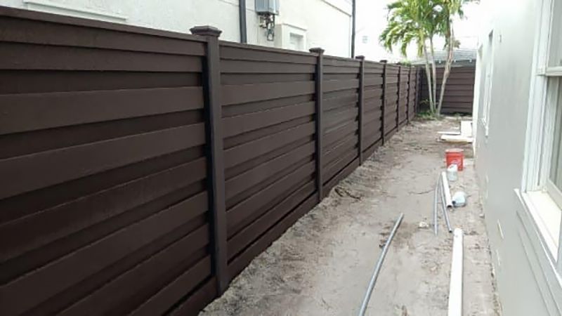 A wooden fence is being built in the backyard of a house.