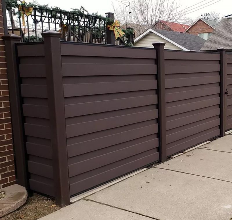 A brown fence with a brick building in the background