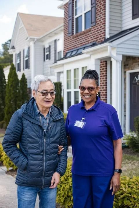 Nurse assists an older person walking in a living room, holding his arm. Sunlight streams in. Nurse assists an older person walking in a living room, holding his arm. Sunlight streams in.
