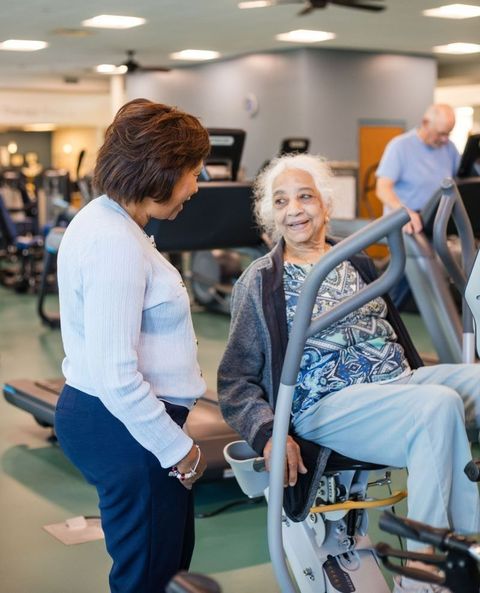 Caregiver in blue scrubs assists an older person using a walker in a home setting. Caregiver in blue scrubs assists an older person using a walker in a home setting.