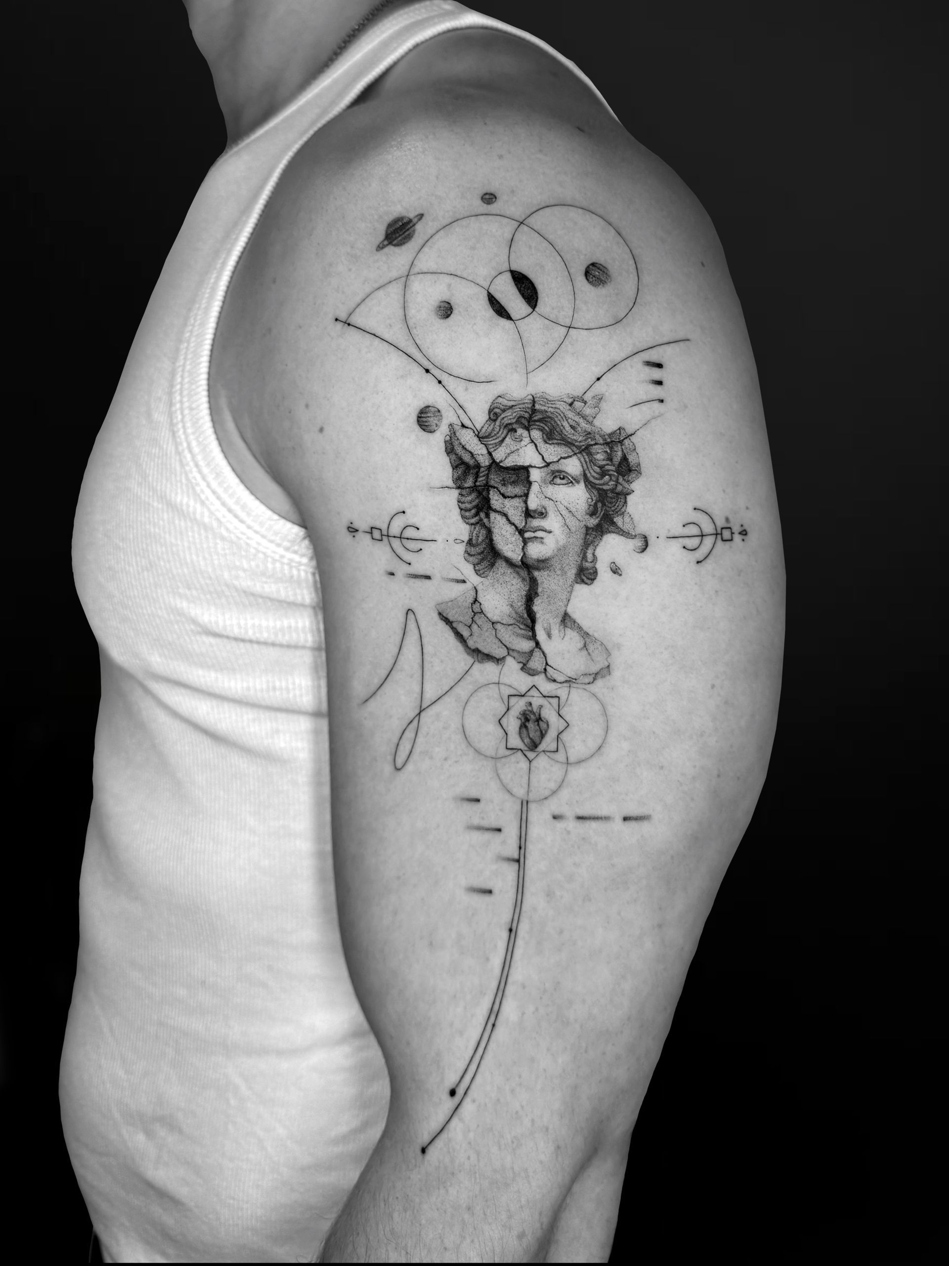 A detailed arm tattoo of a classical bust surrounded by geometric cosmic symbols, planetary orbits, and thin linework.
