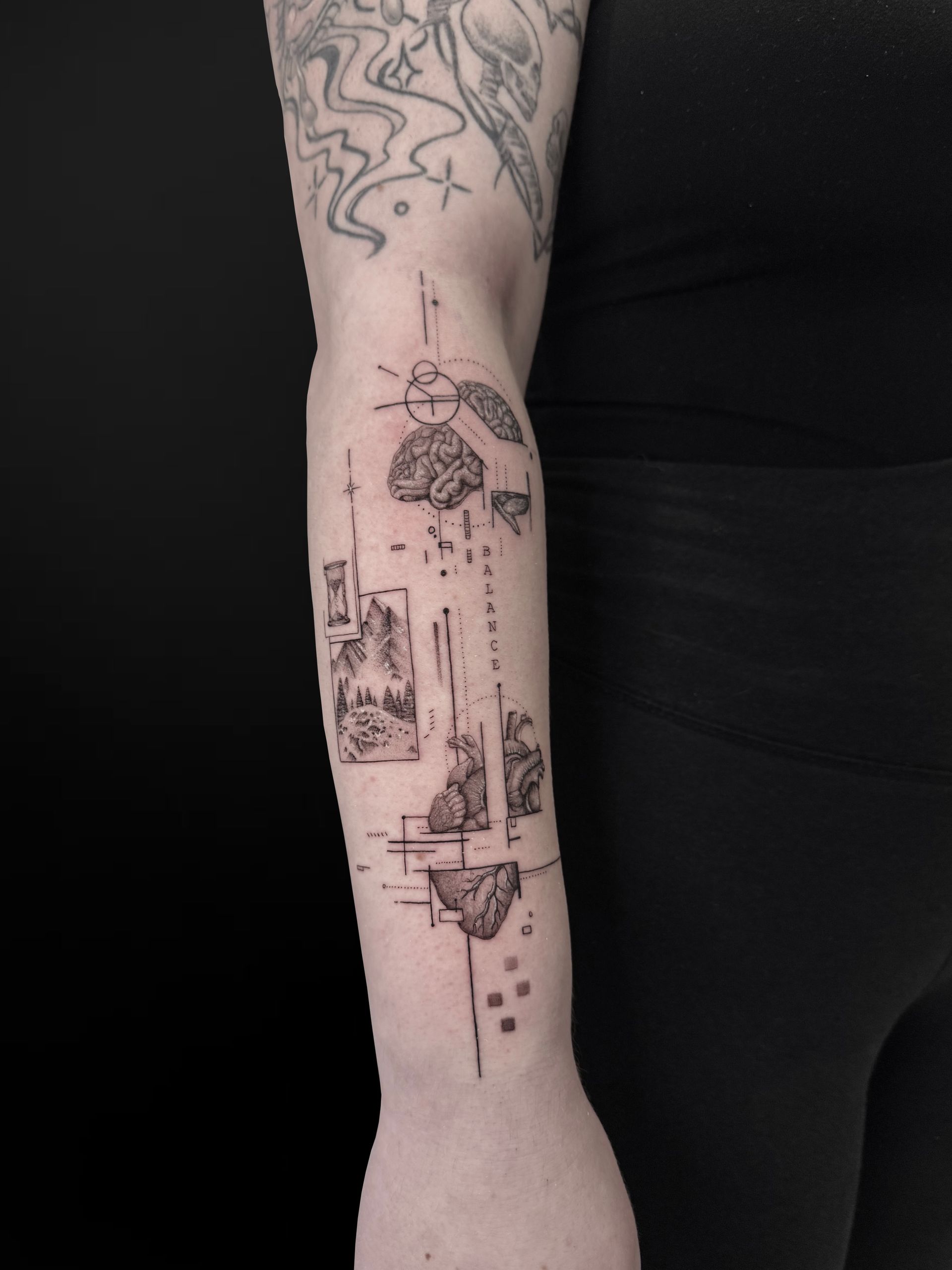 A detailed, fine-line tattoo on a forearm featuring geometric shapes, abstract landscape scenes, and a small hourglass.