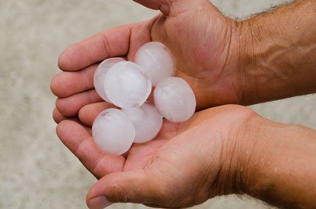 A person is holding a pile of hail in their hands.