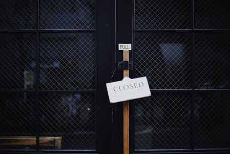 A closed sign is hanging on the door of a building.