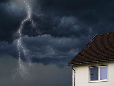 There is a house in the foreground and lightning in the background.