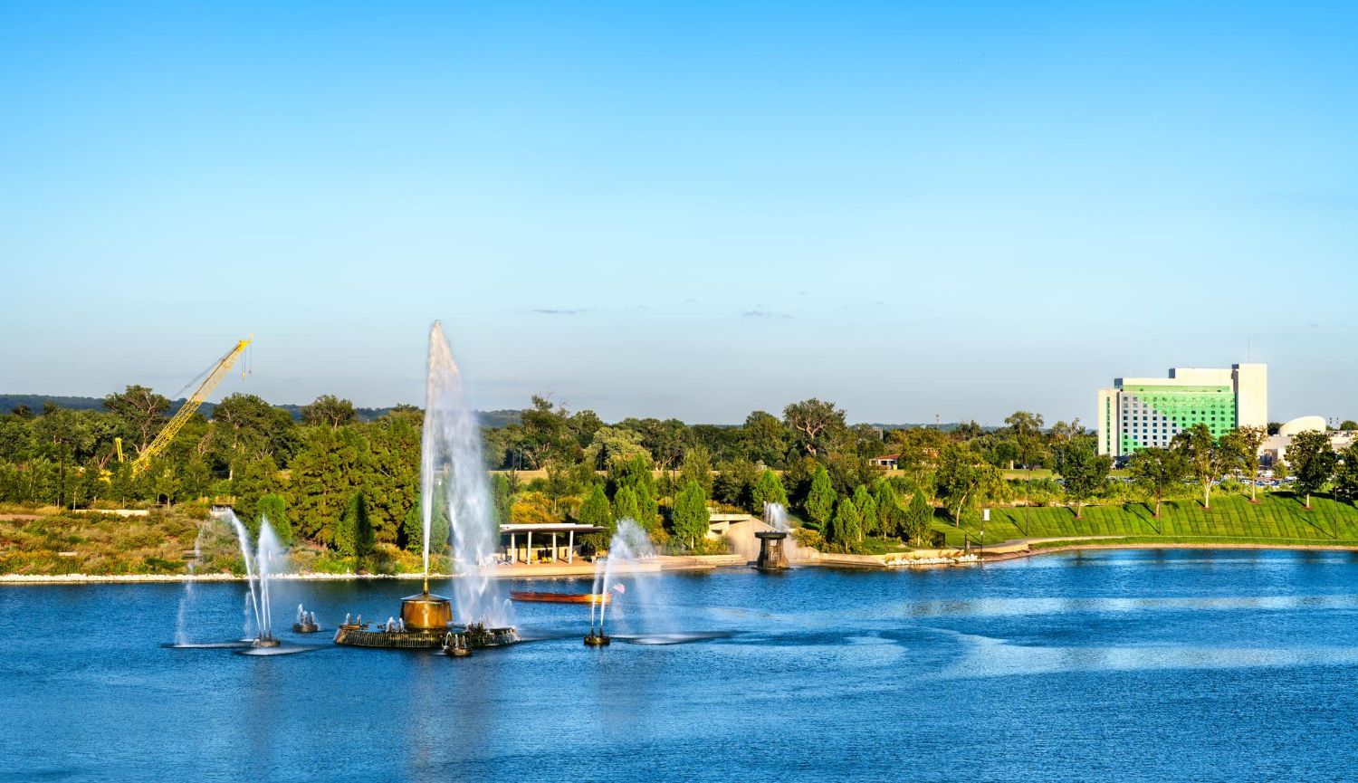 A group of people are walking across a bridge over a river in a park.