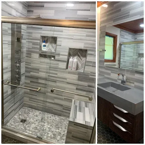 A renovated bathroom featuring a glass-enclosed shower with grey stone tiles and a vanity with a dark cabinet.