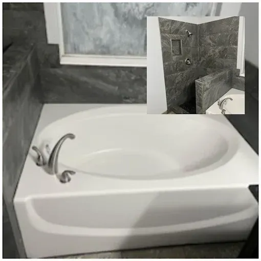 A white oval soaking tub with a silver faucet set against dark grey tiled walls, with an inset of the adjoining shower.