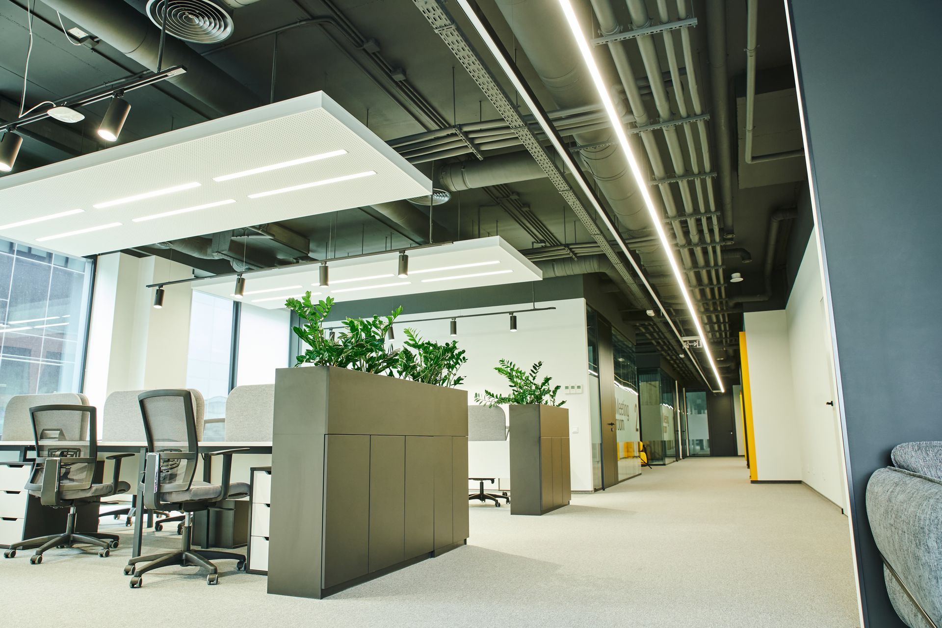 Modern office interior with LED linear lighting installed on ceiling over open workspace and corridor